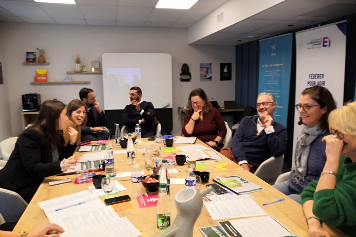 Participants en séance de travail autour d'une table, certains rient